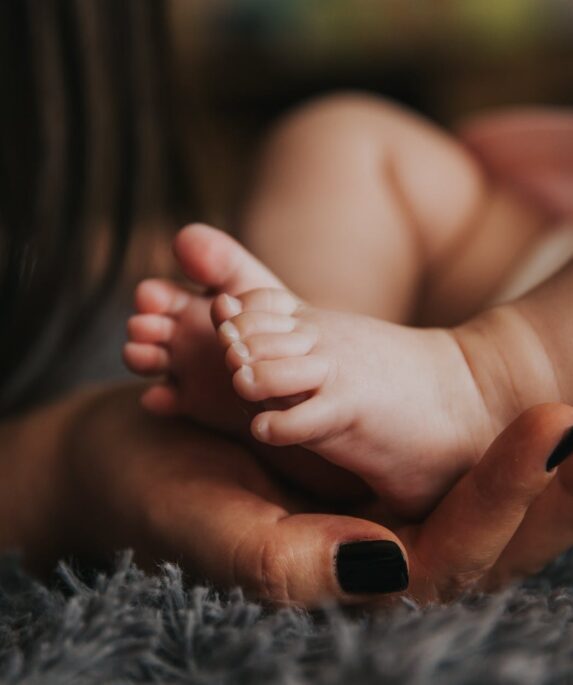 person holding baby s feet in selective focus photography